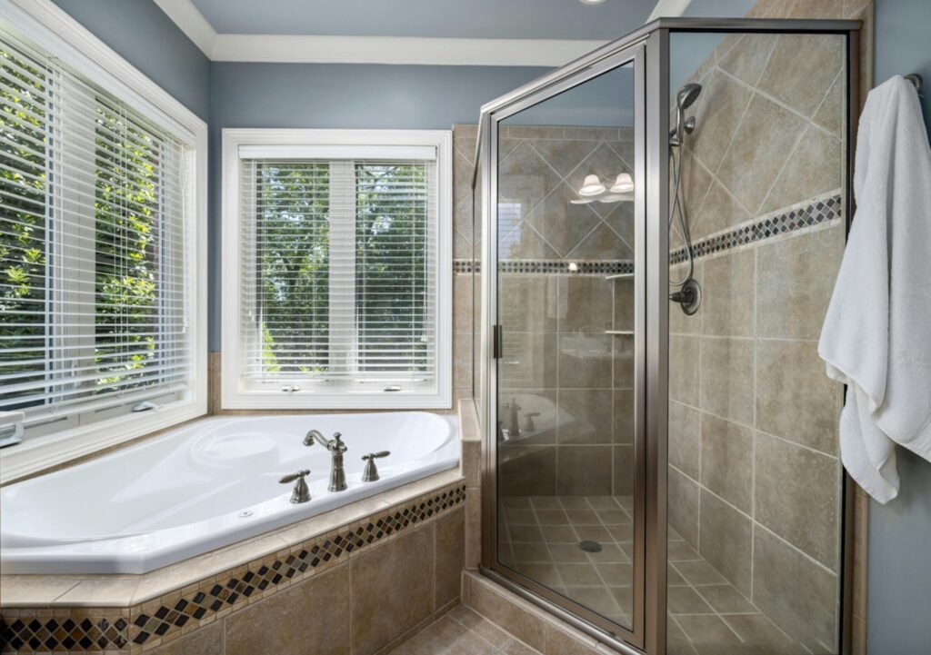 Elegant bathroom with glass shower, soaking tub, and large windows offering natural light.