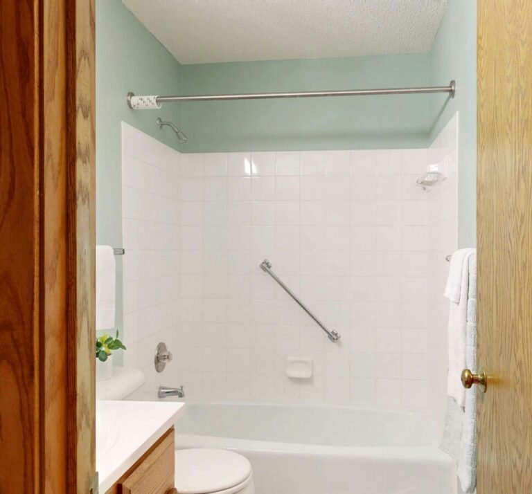 Clean and modern bathroom featuring white ceramic tiles and a bathtub.